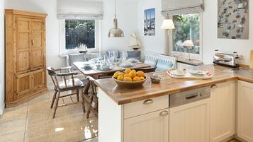 A kitchen with a wooden island, white cabinetry, and a view of the outdoors through a window.