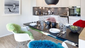 A modern kitchen with white cabinets, a black countertop, and a hanging light fixture. - Herzlich Willkommen im Appartement Inseltraum (List)