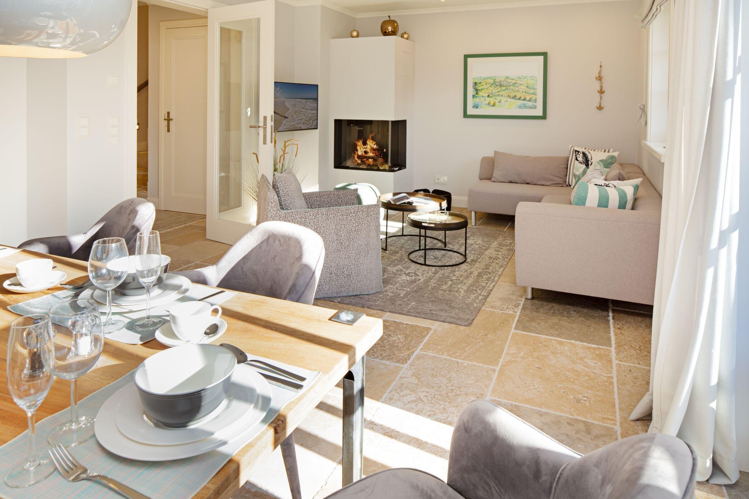 A modern living room with a fireplace, a dining area with a table set for two, and a comfortable sofa.