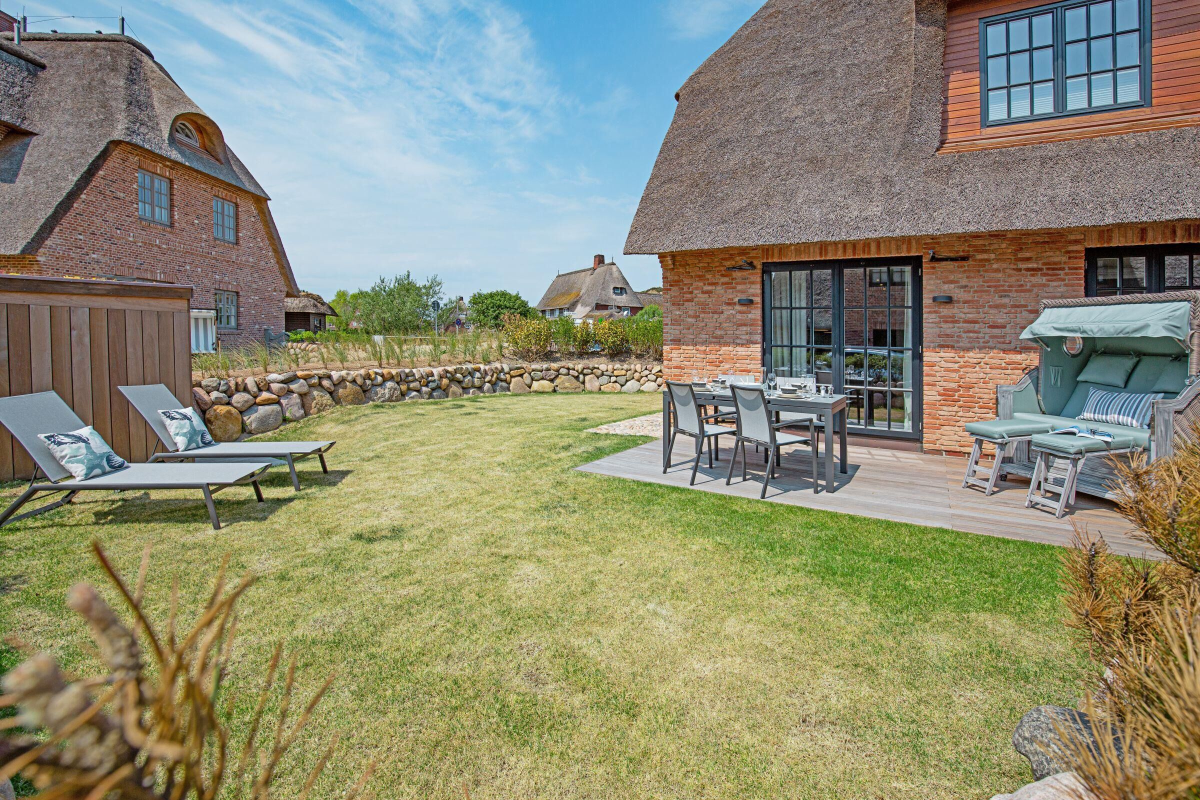 Un jardin avec un espace repas, des chaises longues et un barbecue.