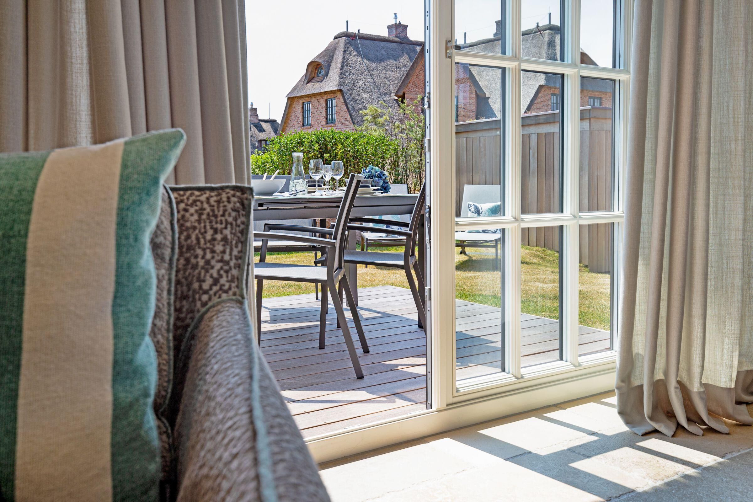 Een kamer met een schuifdeur naar een terras, een eettafel met stoelen en uitzicht op woongebouwen.