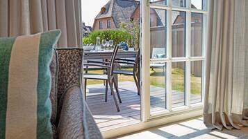 Een kamer met een schuifdeur naar een terras, een eettafel met stoelen en uitzicht op woongebouwen.