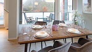 A dining table set with plates, glasses, and cutlery, with a view of trees and a balcony in the background. - Herzlich Willkommen im Appartement Priel (List)