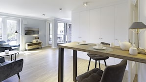Eine moderne Küche mit Holztisch, weißen Schränken und einem Essbereich mit Stühlen.