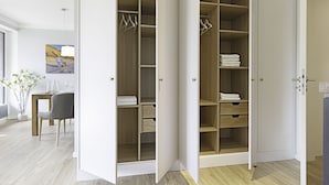 Ein modernes Zimmer mit Holzboden, einem Esstisch mit Stühlen und einem großen begehbaren Kleiderschrank mit geöffneten Türen.