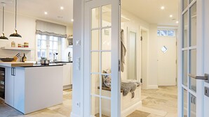 A spacious kitchen with a central island, a dining area with a table and chairs, and a large open space leading to a bathroom with a shower and a towel hanging on the wall. - Herzlich Willkommen im Ferienhaus Trauminsel (List)