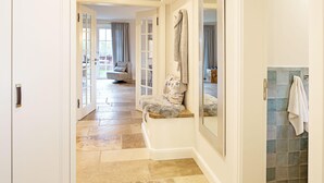 A hallway with a bench, a mirror, and a tiled wall. - Herzlich Willkommen im Ferienhaus Trauminsel (List)