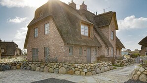 Een traditioneel bakstenen huis met een steile dakschild, stenen muren en een pad van stenen naar de ingang.