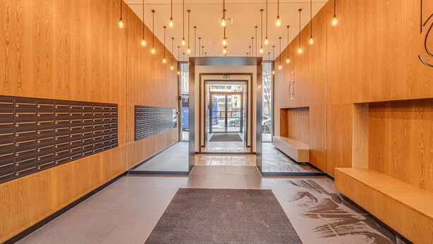 A modern hallway with wooden walls, a tiled floor, and hanging lights. - RentPlanet - Apartament Wyszyńskiego (Wroclaw)