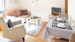 Una sala de estar moderna con sofá, mesa de centro y comedor listo para una comida.