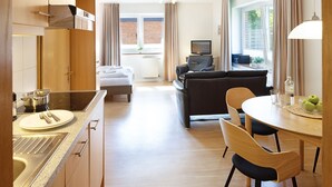 A modern hotel room with a kitchen, dining area, and living space. - Herzlich Willkommen im Appartement Koje (List)