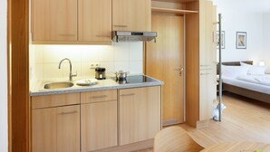A compact kitchen with wooden cabinets, a stainless steel sink, and a compact stove. - Herzlich Willkommen im Appartement Koje (List)