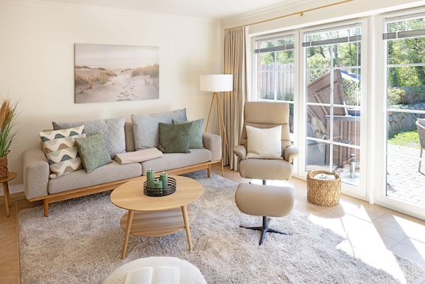 A living room with a sofa, armchair, coffee table, and a large window with a view of the outdoors.