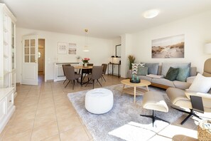 A modern living room with a dining area, a sofa set, and a painting on the wall.