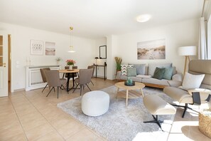 A modern living room with a dining area, a sofa, a coffee table, and a lamp.