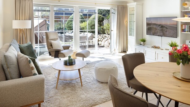 A living room with a sofa, armchairs, a coffee table, a dining table, and a TV. - Herzlich Willkommen im Ferienhaus Olivia (List)