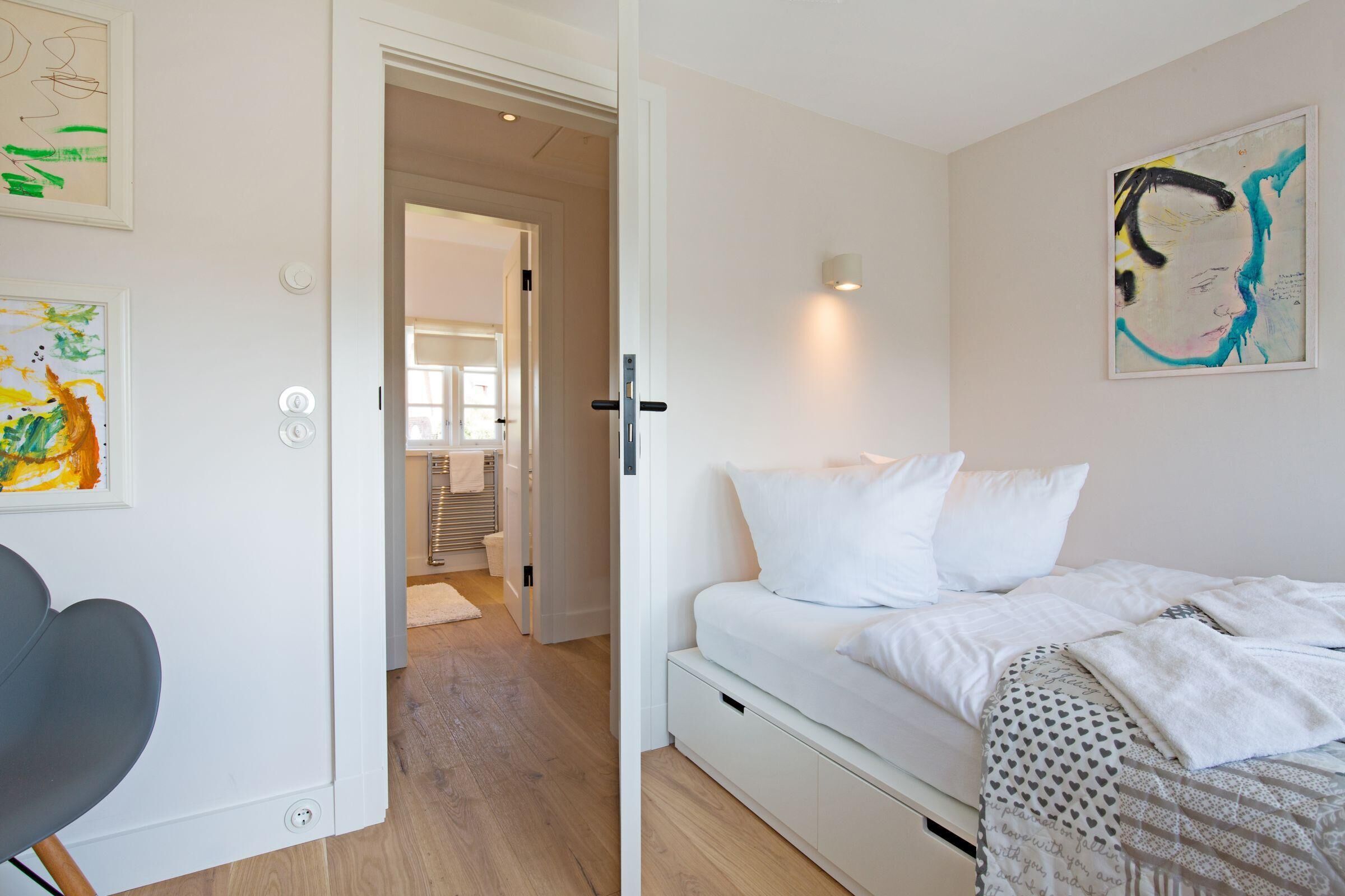 Un dormitorio moderno con una cama, una silla y obras de arte en las paredes.