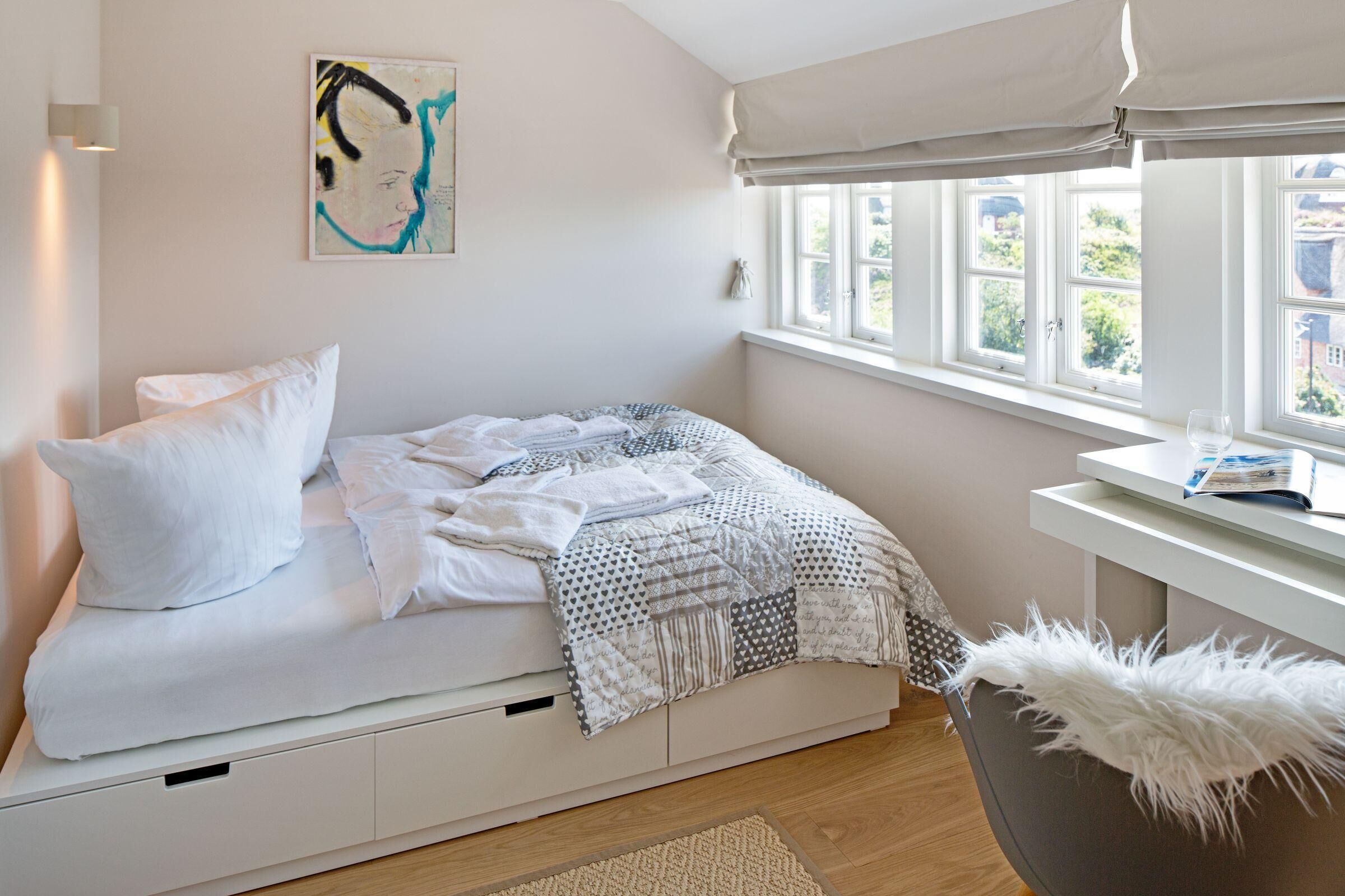 Ein Schlafzimmer mit Bett, Fenster, Schreibtisch und Stuhl.