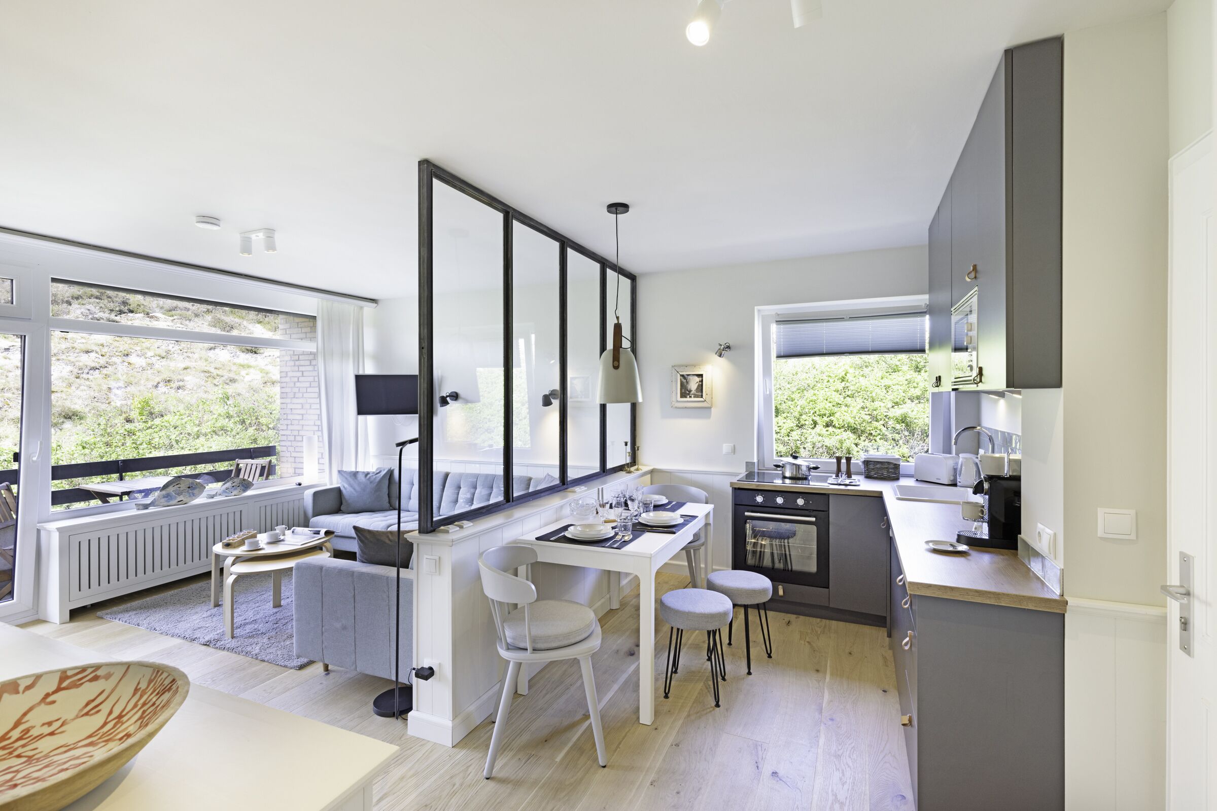 Una cucina moderna con zona pranzo, ampie finestre e vista su spazi verdi.