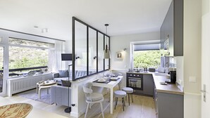 A modern kitchen with a dining area, large windows, and a view of greenery. - Herzlich Willkommen im Appartement Heideblick (List)
