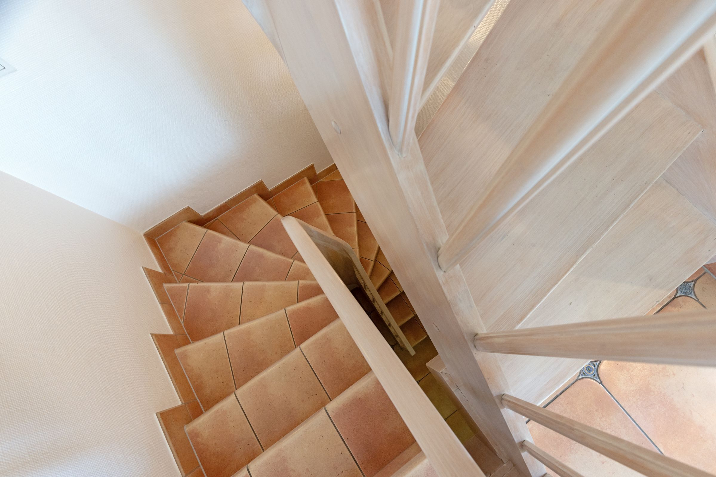 A spiral staircase with wooden steps and handrails, leading upwards in a modern interior.