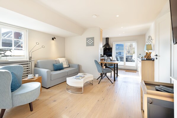 Un salon moderne comprenant un canapé, des fauteuils, une table basse et un coin repas avec une table et des chaises.