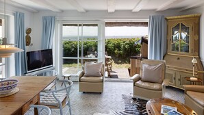 Un salon spacieux doté d’un grand téléviseur, de sièges confortables, d’un coin repas et offrant une vue sur l’extérieur.