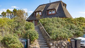 Une maison avec un escalier en pierre à marches abruptes menant à un toit de chaume.