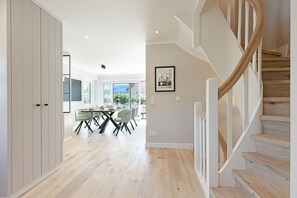 Staircase leads to an upper level with a dining area, kitchen, and large window offering a view of the outdoors.