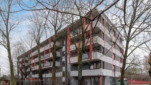 A multi-story building with balconies and a fenced parking area. - Industrial Apartment Fredry with Parking by Noclegi Renters (Kraków)