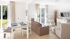 A spacious living room with a dining area, a sofa, and a television.