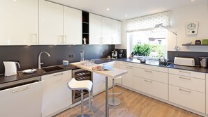 A modern kitchen with white cabinets, a stainless steel sink, and a bar stool.