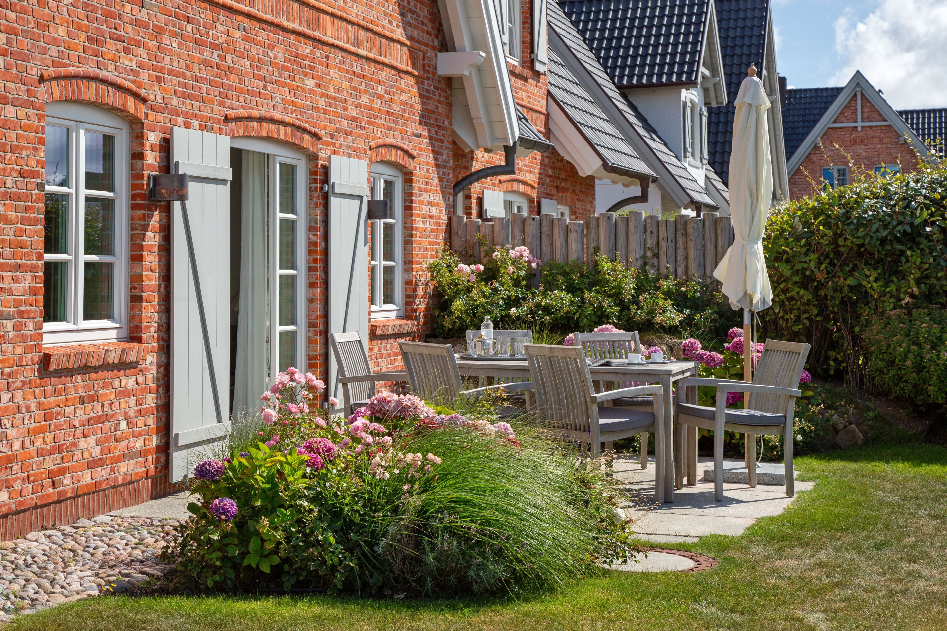 A brick house with a garden patio, outdoor seating, and a fence.