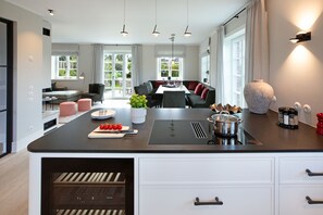 A modern kitchen with an island, built-in appliances, and a dining area with a view.