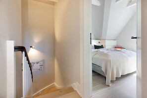 Une chambre à coucher avec un lit, une table de chevet et une lampe fixée au mur.