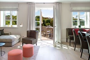 Ein geräumiger Wohnbereich mit Sofa, Sessel, Hocker und einem Esstisch mit Stühlen.
