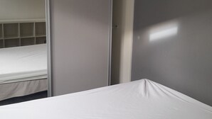 Une chambre avec un lit, une armoire et un miroir.