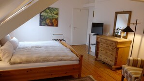 A bedroom with a wooden bed, a dresser, a television, and a mirror. - Landgasthof Kirschgarten (Ingelheim am Rhein)