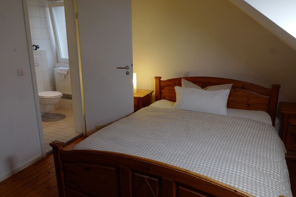 Une chambre à coucher avec un lit en bois, une table de chevet et une fenêtre.
