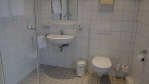 A bathroom with a glass shower enclosure, a sink, a toilet, and a trash bin. - Landgasthof Kirschgarten (Ingelheim am Rhein)