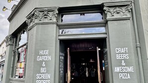 A building entrance with a sign advertising 'Craft Beers & Awesome Pizza'. - The Crown Rooms (London)