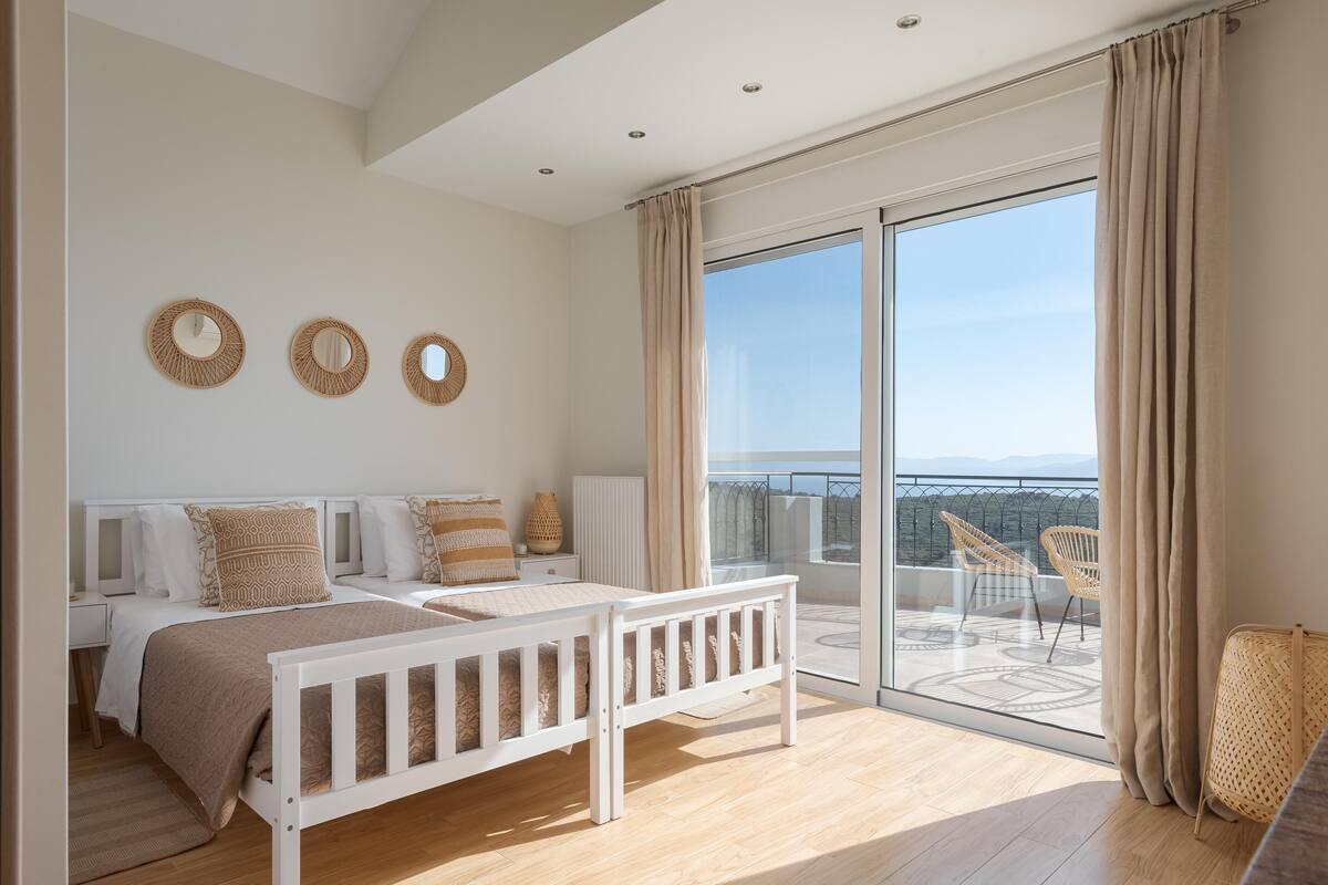 Ein Schlafzimmer mit großem Balkon, einem Bett mit weißem Gestell und drei Spiegeln an der Wand.