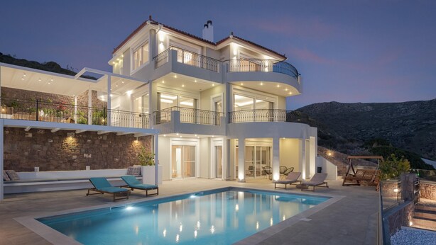 Uma casa moderna de vários andares com piscina, área de estar externa e vista para as montanhas.