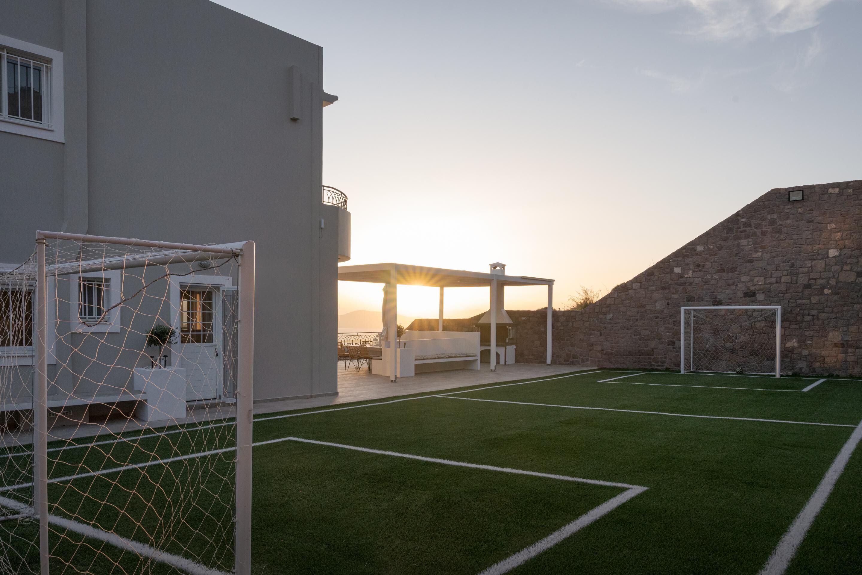 A soccer field with goalposts, a covered seating area, and a stone wall.