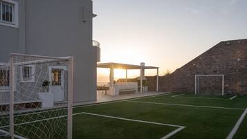 A soccer field with goalposts, a covered seating area, and a stone wall.