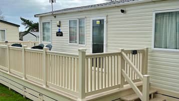 A mobile home with a deck and a staircase leading to the entrance.