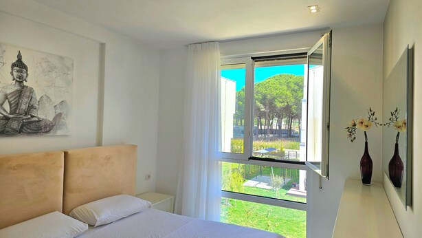 A bedroom with a bed, a window, a Buddha painting, and two vases. - San Pietro Serenity Home (Ishëm)