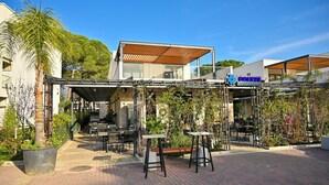 An outdoor seating area with tables and chairs, a wooden pergola, and a sign for 'Breeze Restaurant'. - San Pietro Serenity Home (Ishëm)
