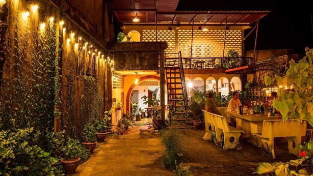 A courtyard with a bar area, potted plants, and a covered seating area. - Baan Kong Hostel (Takua Pa)