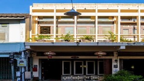 A two-story building with a balcony, potted plants, and a street lamp. - Baan Kong Hostel (Takua Pa)
